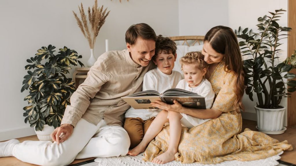 Happy family sitting together on floor, enjoying a book in cozy home environment.